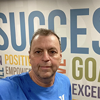 Man standing in front of a wall with motivational words about success and goals.