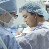 Two surgeons wearing masks and gowns performing a procedure in an operating room.